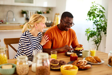 Multiracial couple enjoying breakfast together at home