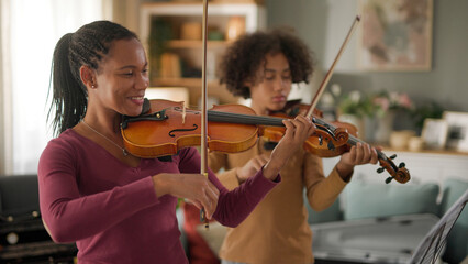 Mother and teenage boy playing violins at home
