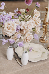 Wedding floristry design. Serving festive wedding table in natural colors with bouquets of roses.