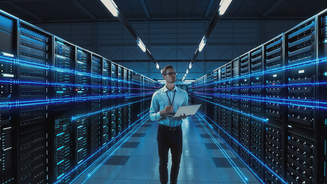 Futuristic Concept: Data Center Chief Technology Officer Holding Laptop, Standing In Warehouse, Information Digitalization Lines Streaming Through Servers. SAAS, Cloud Computing, Web Service