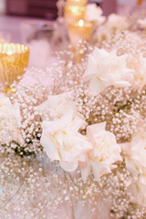 Close-up focus of image is on luxurious composition in white tones of roses and gypsophila .