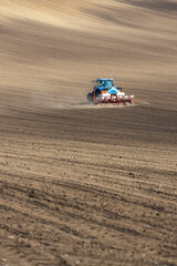 Tractor with seed drill in early spring landscape