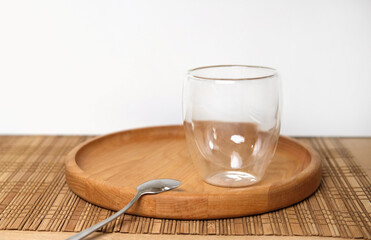 Empty double wall cup for tea or coffee on a table in a restaurant, cafe. Transparent cylindrical crystal mug over wooden table in the bar. Space for copy text. Glass beaker.