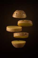sliced raw potato flying freely on a dark brown soft background with a round light gradient. fly vegetable