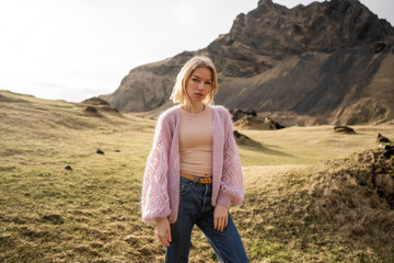 Fashion girl in a purple jacket poses in mountains