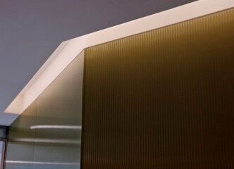 soffit with a cornice illuminated by LED strips in the arch. walls lined with brown wooden plywood....