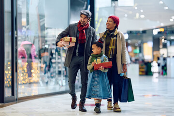 Happy parents and their daughter during Christmas shopping at mall.