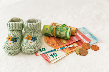 Fototapeta na wymiar Pregnancy planning, motherhood. Children's knitted socks, pregnancy test and money on a white background. Payment of children's money, expensive children's clothing, family budget, expense planning.