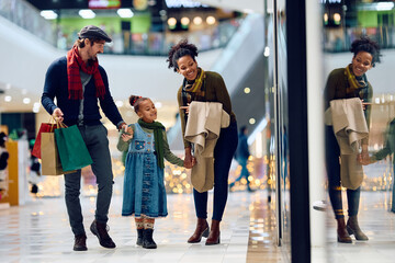 Happy multiracial family window shopping at mall during winter holidays.
