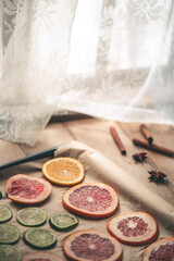 Obraz na płótnie Canvas Sliced orange, tangerine and grapefruit slices on baking sheet, preparing citrus wedges for Christmas garland