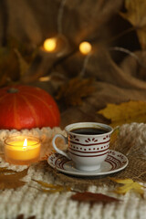 cup of coffee on the autumn background with leaves and candles