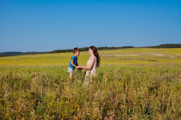 Naklejka premium Mother and son walking in the nature of a rural field