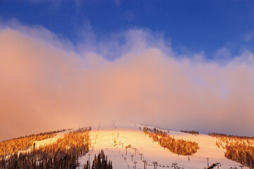 Picturesque sunrise and winter mount covered snow and forest, pink clouds on sky, white snow slopes...