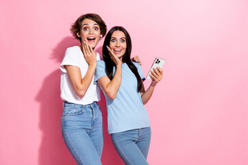 Photo of relatives two people young girls touch hand cheeks surprised amazed holding iphone crazy isolated over pink color background - obrazy, fototapety, plakaty