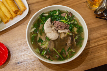 Hanoi-Style Pho Tai Lan, A Savory Bowl of Beef and Chicken and Garlic Soup, Enjoying Noodles and Meat with Chopsticks