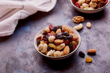 Saucers with mixed nuts. Healthy desserts and snacks. Walnuts, almonds, hazelnuts and cashews. Raisins and cranberries close up