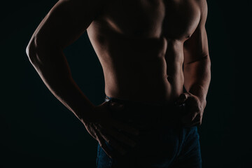 Silhouette photo of strong man showing his abs in studio. Partial shot
