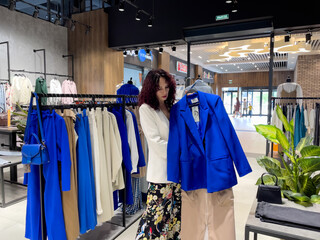 Shopping woman, women's fashion clothes in a store, boutique. Woman choosing clothes in a store