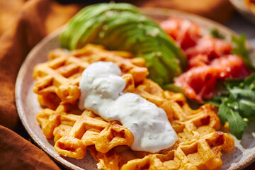 Hearty sweet potato or pumpkin waffles with avocado, salmon, arugula and sauce