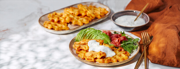 Hearty sweet potato or pumpkin waffles with avocado, salmon, arugula and sauce