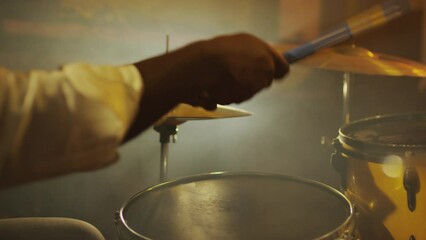 Slowmo closeup of unrecognizable hands of Black male jazz drummer making beat with sticks on hi hats while performing in smoky dark night club