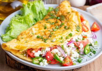 Homemade stuffed omelet on a plate. Egg omelet stuffed with fresh tomatoes, cheese and green parsley. Healthy vegetarian breakfast recipe.