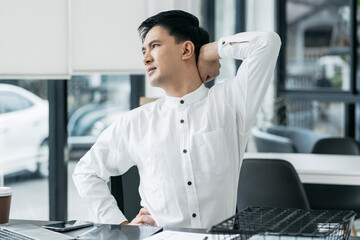 businessman is doing a stretchy posture due to sitting in the office for too long, office syndrome...