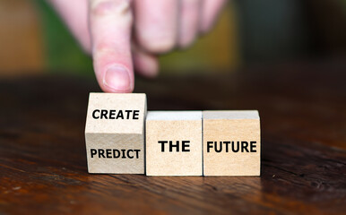 Hand turns wooden cube and changes the expression 'predict the future' to 'create the future'.