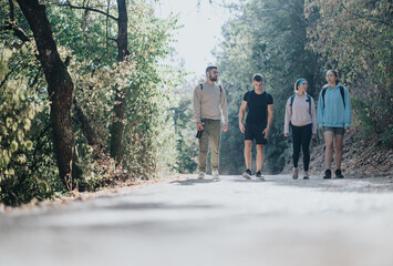 Fototapeta premium Active friends hike through a vibrant autumn forest, engaging in fun conversations. Surrounded by mountains and trees, they embrace a healthy outdoor lifestyle, exploring the natural beauty together.