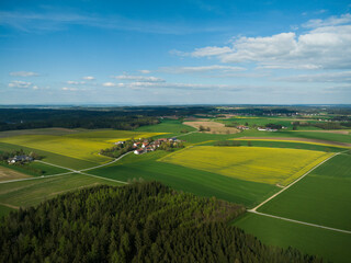 Drone image of rural landscape with different colored crops and forests. Bavaria, Germany