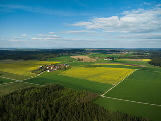 Drone image of rural landscape with different colored crops and forests. Bavaria, Germany