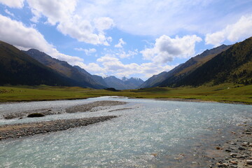 Turgenaksu valley with a river wading on a second stage of Ak-Suu Traverse trek in Karakol, Kyrgyzstan - obrazy, fototapety, plakaty