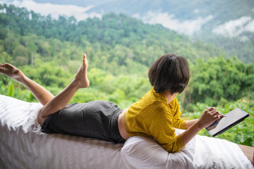 Asian woman freelancer traveler working online using tablet. thinking creative idea in morning of nature cliff mountain.