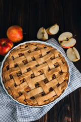 Apple pie in blue form on a dark wooden background with a white kitchen towel. Ready pie. Top view