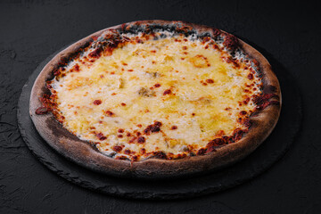black pizza with cheese on stone