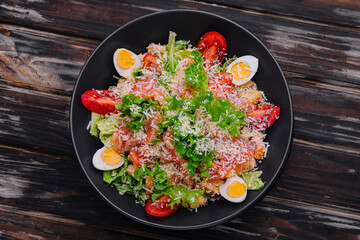 Salad with salmon, lettuce, boiled eggs, cherry tomatoes and parmesan cheese
