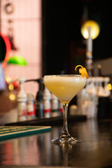 fancy lime glass of yellow orange cocktail on pub counter
