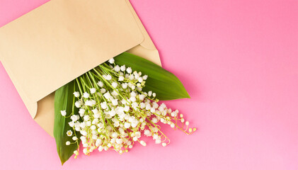 Lily of the valley in an envelope on the pink background. Top view. Copy space.