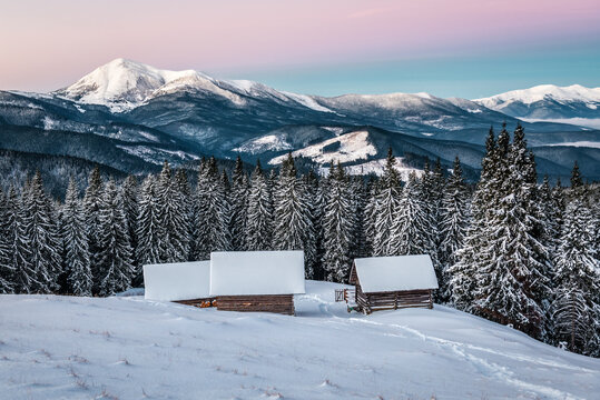 Three abandoned log cabins at beautiful sunrise in winter Carpathian mountains