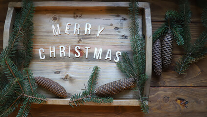 Merry Christmas greetings - Christmas composition of greetings with letters, fir branches and pine cones - wooden background - view from above © Bookaroo68