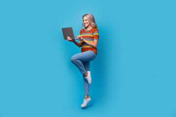 Full length photo of sweet shiny lady wear print shirt jumping communicating modern device isolated...
