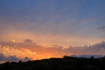 Colourful sunset in the bay of Agios Georgios with dark clouds in front of an intensely orange sky with individual strangely shaped dark wispy clouds on the island of Corfu