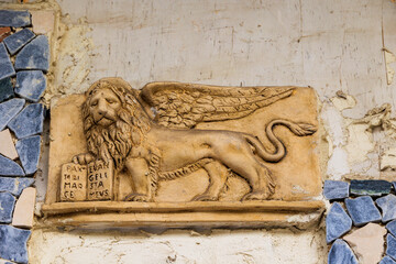 .A stone relief of a winged lion with a book in its hand on a wall on the island of Corfu