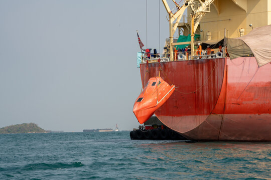 Watertight lifeboat test. Port state control. Lowering orange totally enclosed lifeboat to water. Abandon ship drill. Lifeboat training.