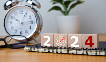 Wooden blocks with letters 2024 with calendar and alarm clock on wooden background representing the...