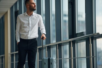 Standing, looking through the windows. Young handsome man in the airport