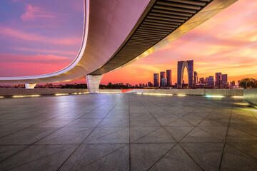 Empty square floor and pedestrian bridge with city skyline at sunset in Suzhou, Jiangsu Province, China.