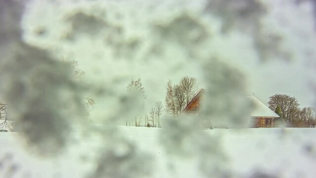 Timelapse shot of a wooden cabin in the middle of snowfall with camera covered with snow on a cold winter day.