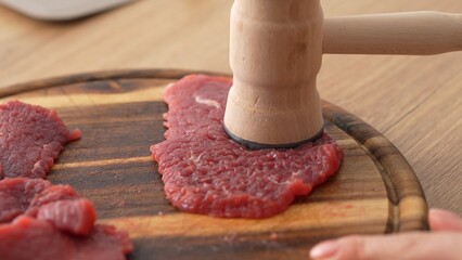 Close-up shot of Tenderizing Beef Steaks on Board.