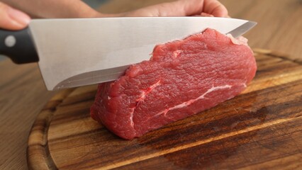 Close-up shot of Slicing Raw Beef on Cutting Board.